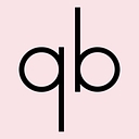 Que Bella logo